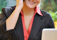 Junge Frau am Laptop telefoniert